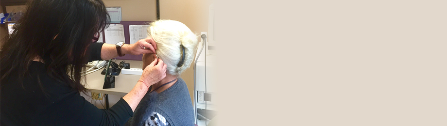 Audiologist placing hearing aid on patient
