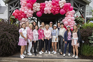 A group of golfers stand infront of a large baloon arch