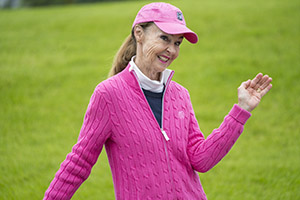 A woman in pink golf clothing smiles