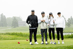 four golfers smile whie in the rain