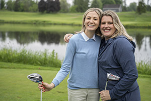 Two golfers smile for holding their drivers