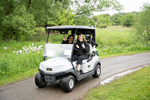 Two golfers smile in a golf cart