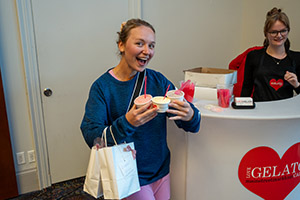A woman smiling holding three cups of ice cream