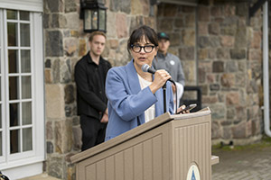 A woman wearing blue speaks into a microphone