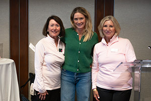 Three women stand shoulder to shoulder smiling for a photo