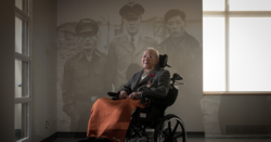 Veteran Beong Soo Kim photographed in front of a projected photo of himself and others during the war