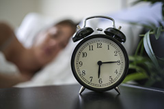 A person sleeping and an alarm clock