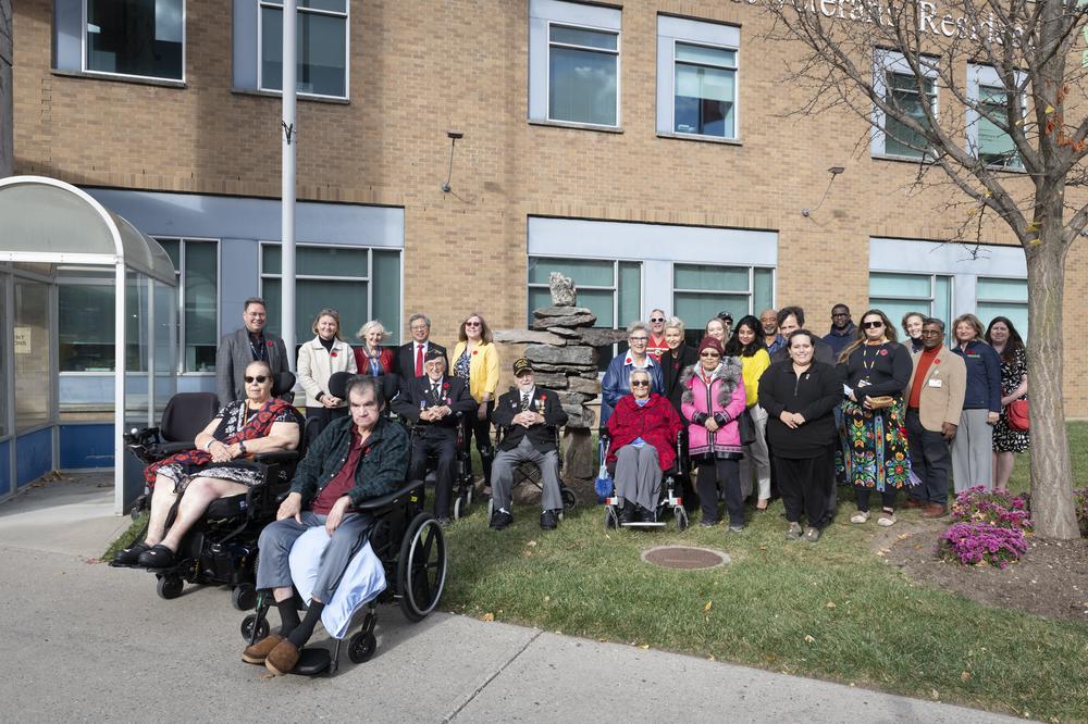 Participants of the Indigenous Veterans Day ceremony gather beside the Inukshuk outside the Sunnybrook Veterans Centre. 